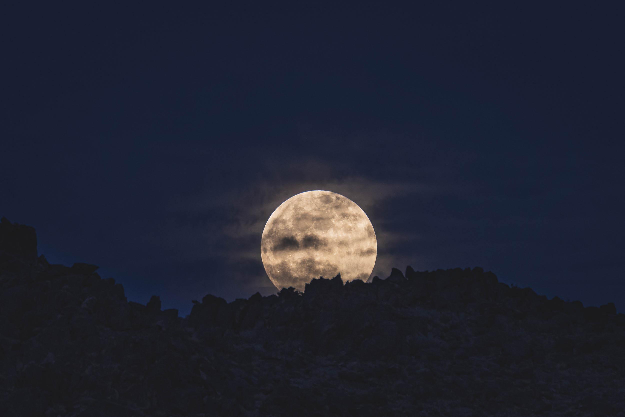 The moon rising over rock formations in Joshua Tree