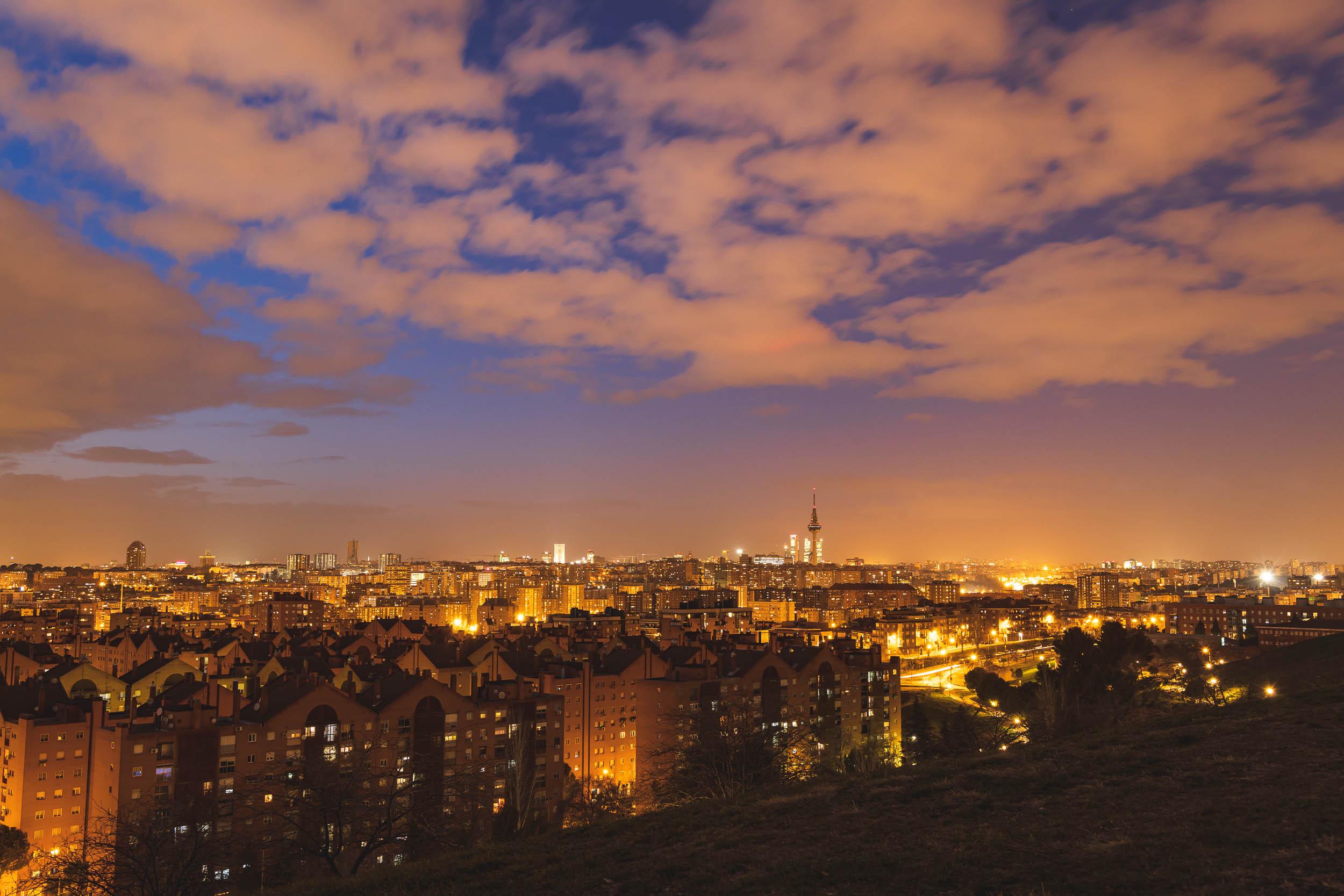 Fluffy clouds follow rainshowers as the sun sets in the sky over Madrid