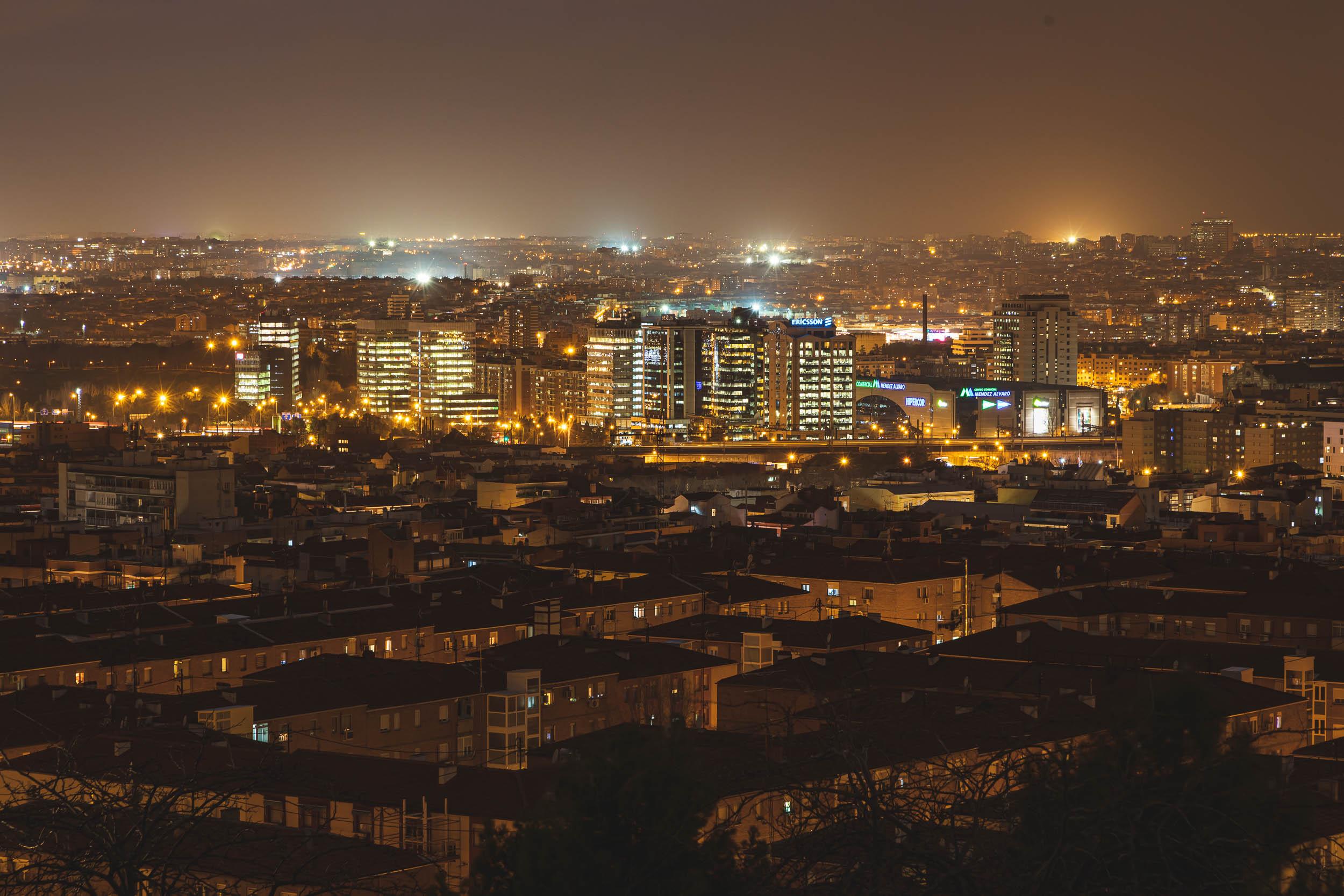 A train moving through Madrid at night surrounded by buildings