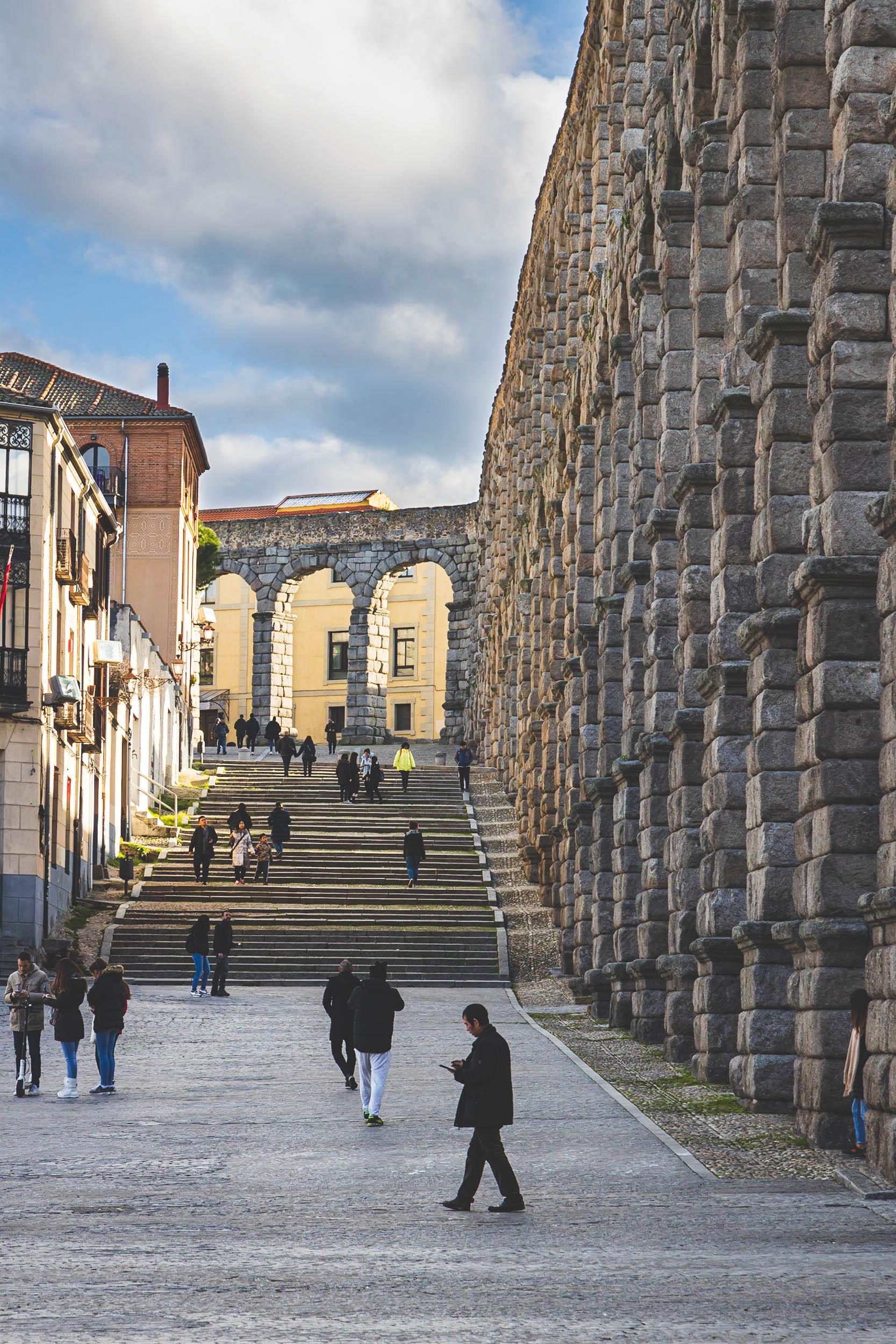 The aqueduct in Segovia shining in the morning light as people go about their day
