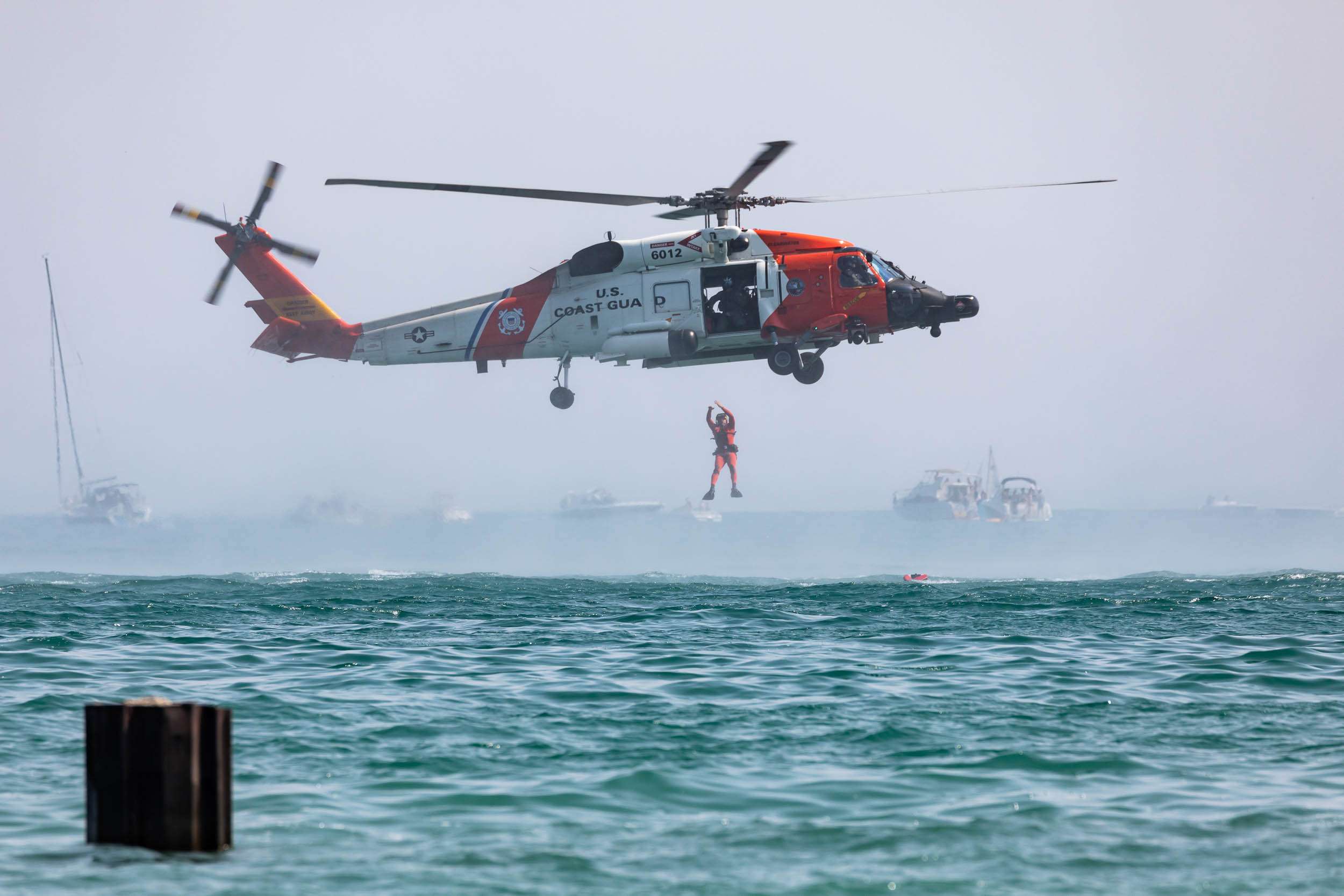 A rescue diver jumps from a US Coast Guard helicopter