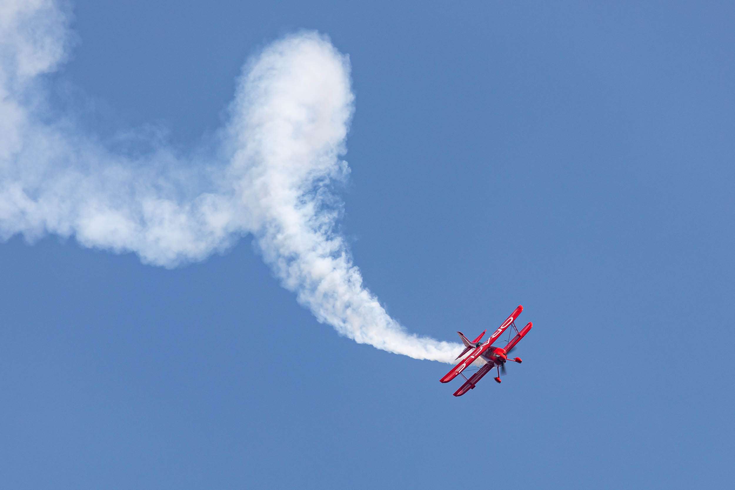 A red biplane flown by Sean D. Tucker performs quick barrel rolls